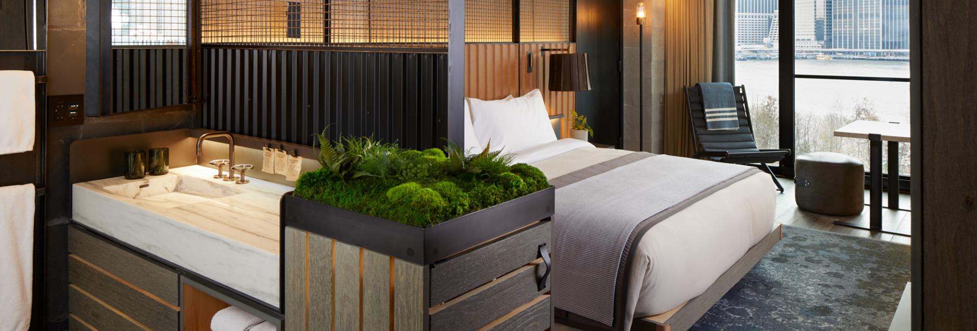 A king sized bed in a suite with a view of the Manhattan skyline